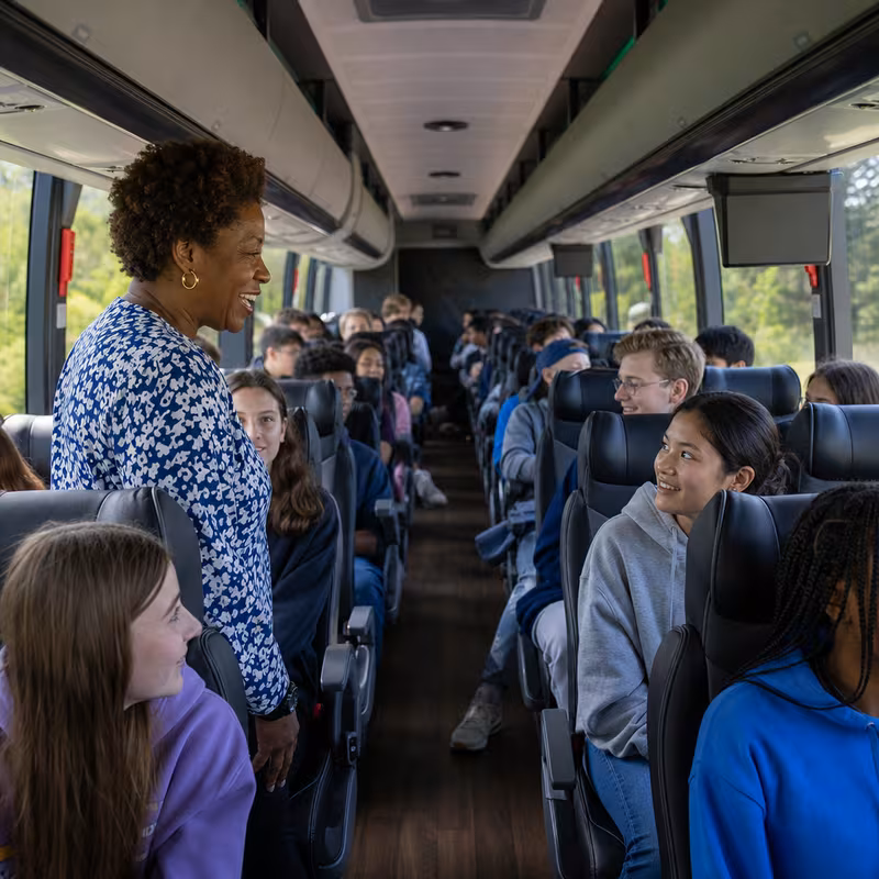 Group boarding a white charter bus for School Transportation transportation in Washington